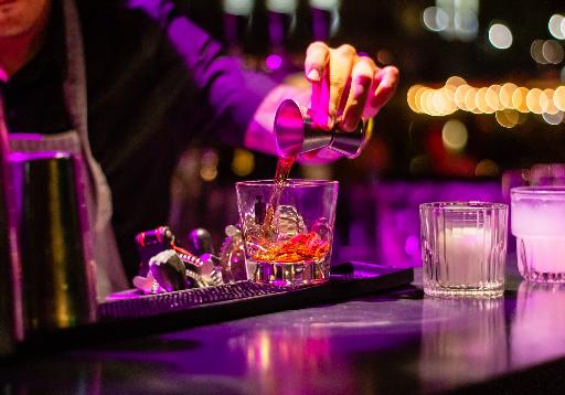 person pouring liquor in clear drinking glass